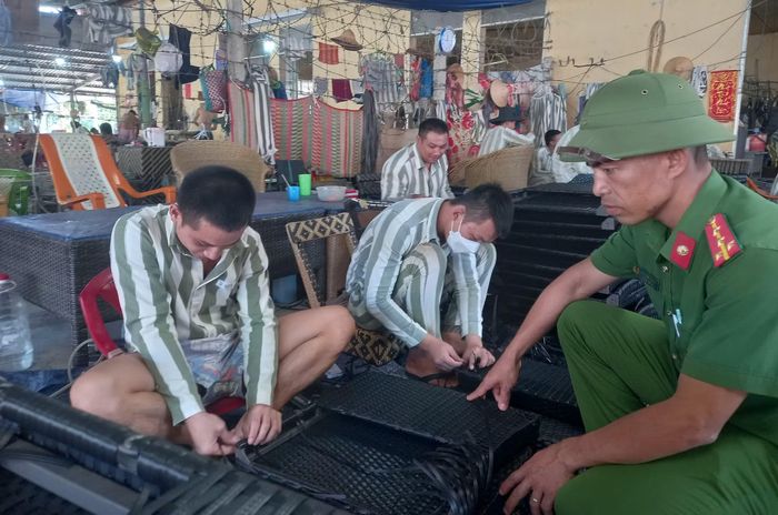 Cán bộ quản giáo kiểm tra phạm nhân thao tác kỹ thuật đan kết sản phẩm thủ công mỹ nghệ. Ảnh: Hữu Toàn.