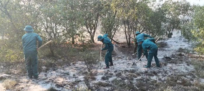 Lực lượng chức năng và người dân địa phương tiến hành phát quang làm đường băng cản lửa để khống chế đám cháy.