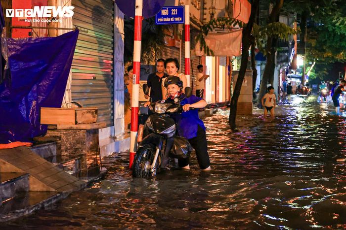 Tại đường Doãn Kế Thiện, gần 21h, đường vẫn chìm trong nước. Nhiều đoạn ngập gần nửa bánh xe máy khiến các phương tiện di chuyển rất khó khăn.