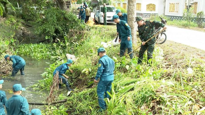 Dưới nắng nóng, cán bộ, chiến sĩ dân quân phát quang bụi rậm, dọn sạch tuyến kênh dài hơn 2.000m trong hoạt động “Quân - Dân chung sức” vì cộng đồng. Ảnh Trung Ngãi