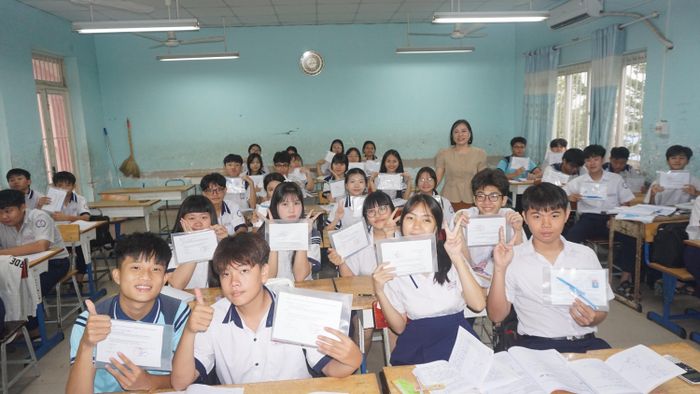  Cô Nguyễn Thị Hải Lý tặng học sinh bìa sơ mi để đựng những vật dụng cần thiết vào phòng thi. Ảnh: NQ 