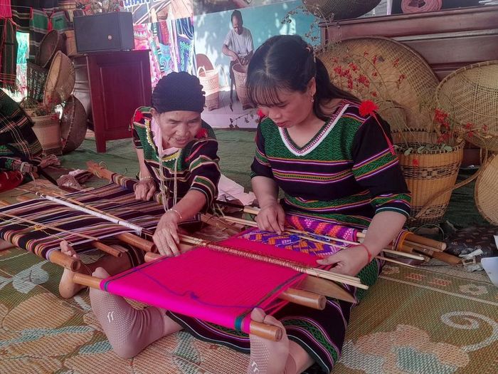 Bà Thị Y Rơ (76 tuổi, người dân tộc M’nông) chỉ dạy nghề dệt thổ cẩm cho người dân trong thôn. Ảnh: K GƯỈH-TTXVN