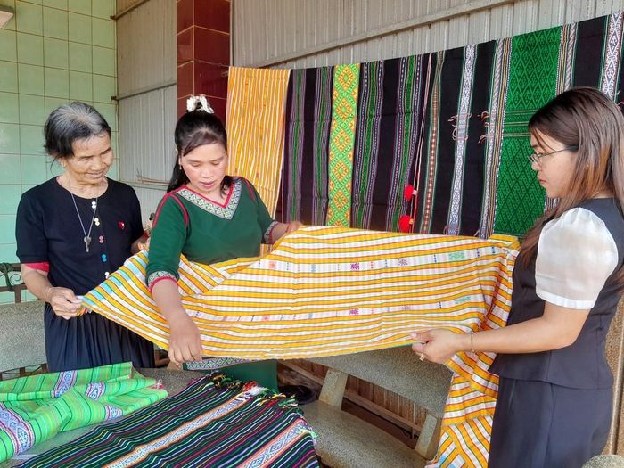 Bà Thị Y Rơ (trái) giới thiệu tấm thổ cẩm đã hoàn chỉnh cho chuyên viên phòng văn hóa-xã hội xã Bù Gia Mập. Ảnh: K GƯỈH-TTXVN