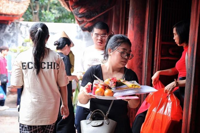 Phụ huynh mang lễ vật vào khu thờ tự, đồng hành cùng con trong giai đoạn áp lực trước kỳ thi. Ảnh: Phạm Tuấn Anh - TTXVN