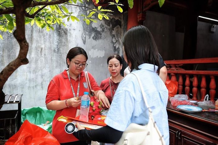 Phụ huynh và học sinh chuẩn bị lễ vật trước khi vào dâng hương, cầu mong kỳ thi diễn ra suôn sẻ. Ảnh: Phạm Tuấn Anh - TTXVN
