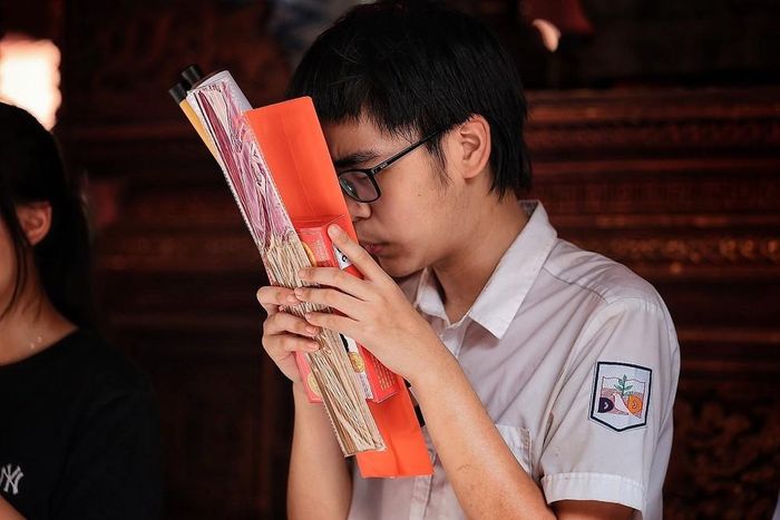 Nam sinh ôm lễ vật, thành tâm cầu may trước kỳ thi tuyển sinh lớp 10. Ảnh: Phạm Tuấn Anh - TTXVN