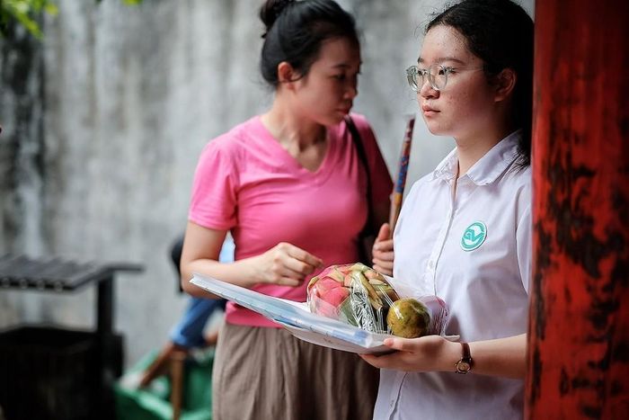 Một nữ sinh mang theo lễ vật, sách vở đến Văn Miếu để cầu mong việc học hành, thi cử thuận lợi. Ảnh: Phạm Tuấn Anh - TTXVN
