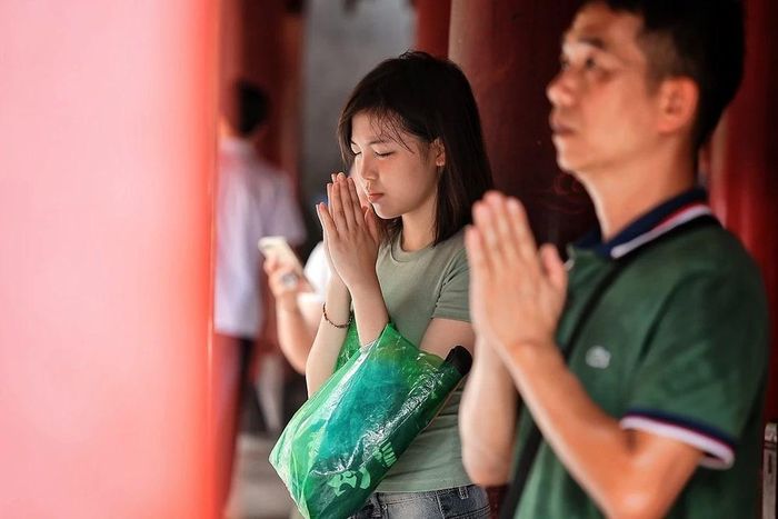 Nhiều bạn trẻ chắp tay cầu nguyện, mong có thêm sự tự tin và bình tĩnh trước khi bước vào phòng thi. Ảnh: Phạm Tuấn Anh - TTXVN