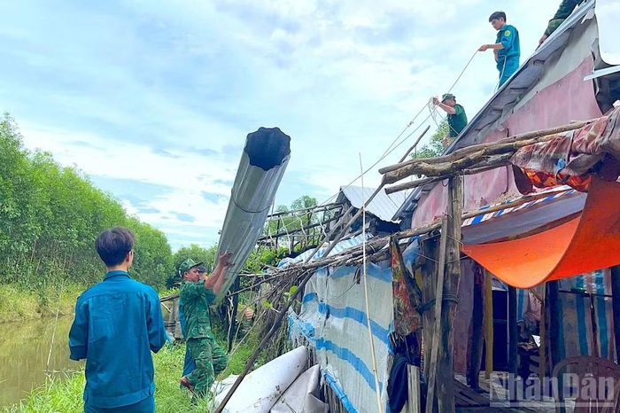 Cán bộ, chiến sĩ Đồn biên phòng Khánh Tiến cùng lực lượng Quân sự xã U Minh (tỉnh Cà Mau) hỗ trợ người dân che chắn lại nhà sau thiên tai.