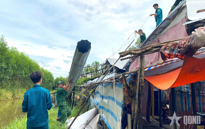 Cán bộ, chiến sĩ Đồn Biên phòng Khánh Tiến cùng lực lượng dân quân Ban CHQS xã U Minh hỗ trợ người dân che chắn lại nhà sau thiên tai.