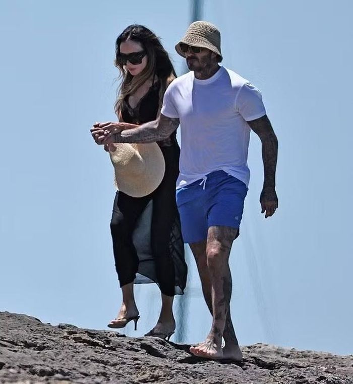 Beckham đi chân trần, đỡ bà Beck đang loạng choạng di chuyển trên bãi đá.