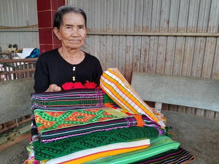 Nghệ nhân Thị Y Rơ (76 tuổi, người dân tộc M’nông) với tấm thổ cẩm đã dệt hoàn chỉnh. (Ảnh: K GƯỈH/TTXVN)