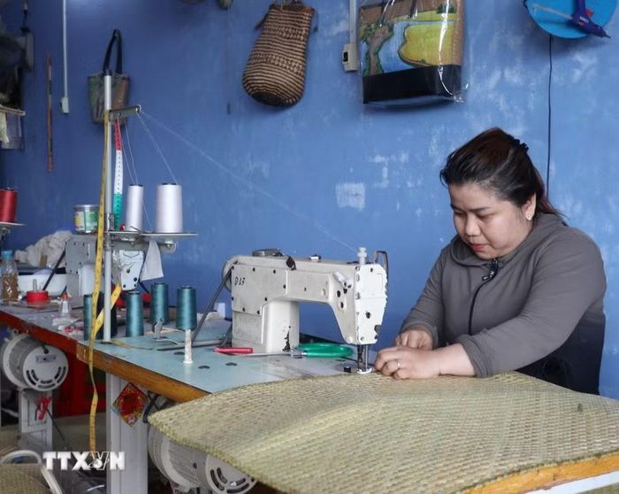 Phụ nữ xã Giang Thành may gia công sản phẩm từ cỏ bàng. (Ảnh: Văn Sĩ/TTXVN)