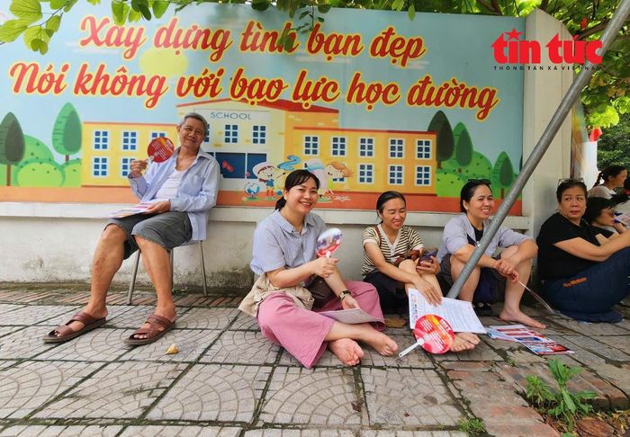 Phụ huynh đợi con bên ngoài điểm thi Trường Trung học cơ sở Thanh Xuân Trung trong điều kiện thời tiết khá oi bức.