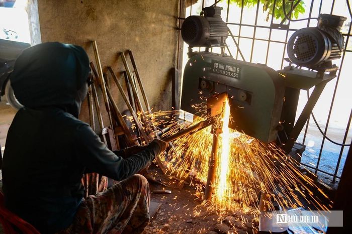 Phóng viên có mặt tại làng nghề, đứng cách lò rèn vài mét vẫn cảm nhận rõ luồng nhiệt rát mặt. Ngoài trời nắng gắt gần 40 độ C, bên trong xưởng, sức nóng từ than lửa và kim loại nung đỏ khiến không khí đặc quánh, ngột ngạt.
