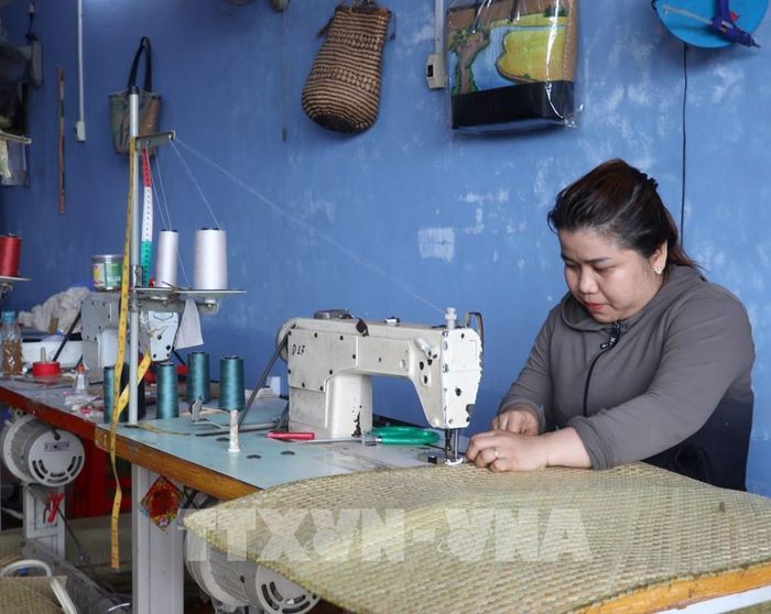 Phụ nữ xã Giang Thành may gia công sản phẩm từ cỏ bàng. Ảnh: Văn Sĩ - TTXVN 