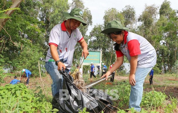 Người dân tham gia thu gom rác trên tuyến đường dọc Khu du lịch sau buổi lễ. Ảnh: Hồng Thái-TTXVN