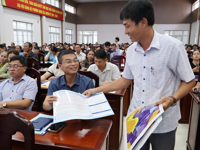 Cán bộ Chi cục Thủy sản và Kiểm ngư tỉnh phát tờ rơi tập huấn chống khai thác IUU cho ngư dân. Ảnh: THÙY TRANG
