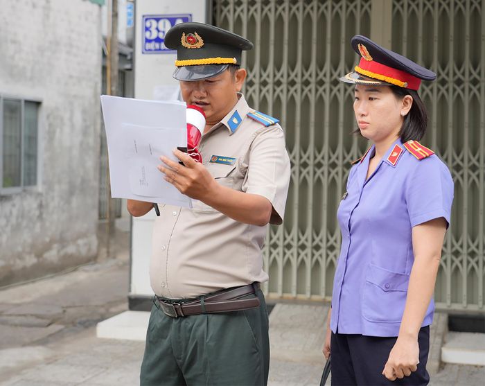 Chấp hành viên đọc quyết định cưỡng chế trước sự chứng kiến của lực lượng chức năng và đông đảo người dân chứng kiến.