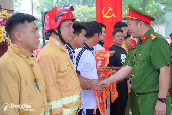 Ban tổ chức trao cờ lưu niệm cho các đội tham gia Hội thi nghiệp vụ chữa cháy và cứu nạn, cứu hộ “tổ liên gia an toàn phòng cháy, chữa cháy” Cụm thi số 4 năm 2026. Ảnh: Lê Duy