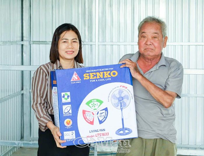 Bà Phạm Ngọc Hiền, Phó Trưởng phòng Văn hóa - Xã hội xã Đất Mới, trao tặng quà chúc mừng ông Tô Văn Xiếu
