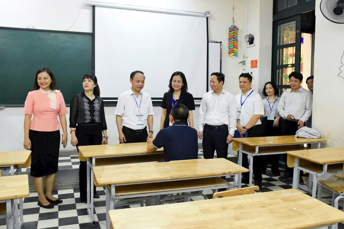 Đại diện Ban Chỉ đạo thi, tuyển sinh thành phố trò chuyện cùng phụ huynh thí sinh tại điểm chờ đặt tại Trung tâm Giáo dục nghề nghiệp - Giáo dục thường xuyên Nguyễn Văn Tố. Ảnh: Phạm Thảo.