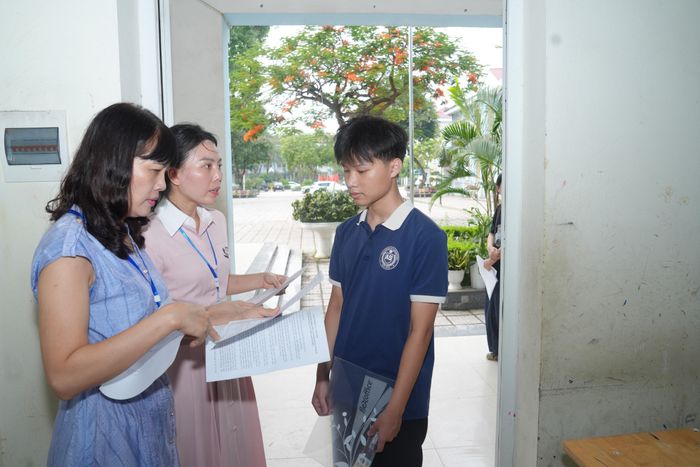 Giám thị kiểm tra thẻ dự thi của thí sinh trước khi vào phòng thi.