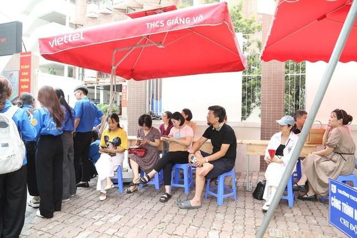 Nhiều bậc phụ huynh nán lại bên ngoài khu vực trường thi để đồng hành cùng con trong buổi làm thủ tục.