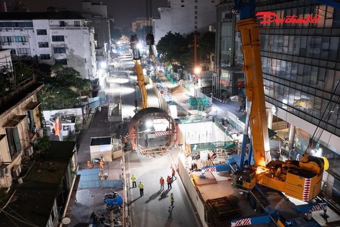 Theo ông An, máy TBM gồm hai bộ phận chính là phần thân TBM và dàn xe phụ trợ phía sau. Riêng phần thân máy nặng khoảng 500 tấn, trong đó có những cấu kiện nặng gần 100 tấn. Khó khăn lớn nhất là việc nâng hạ những cấu kiện siêu nặng trong điều kiện mặt bằng rất chật hẹp giữa trung tâm Hà Nội, xung quanh là nhiều tòa nhà lớn và hệ thống hạ tầng dày đặc. Nếu tính toán không cẩn thận, khi cẩu hạng nặng xoay chuyển có thể xảy ra va chạm với công trình xung quanh. Chính vì vậy, toàn bộ vị trí cẩu hạ, bố trí xe vận chuyển, hệ thống xi nhan, móc cáp hay bán kính hoạt động của cẩu đều phải được tính toán cực kỳ chi tiết để bảo đảm mọi thao tác diễn ra đúng kế hoạch và tuyệt đối an toàn.