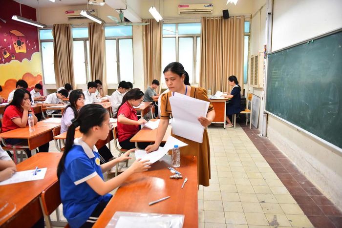 Giám thị phát giấy thi làm bài môn Ngữ văn sáng 30/5 tại điểm thi THPT Nguyễn Trãi. Ảnh: Quang Vinh.