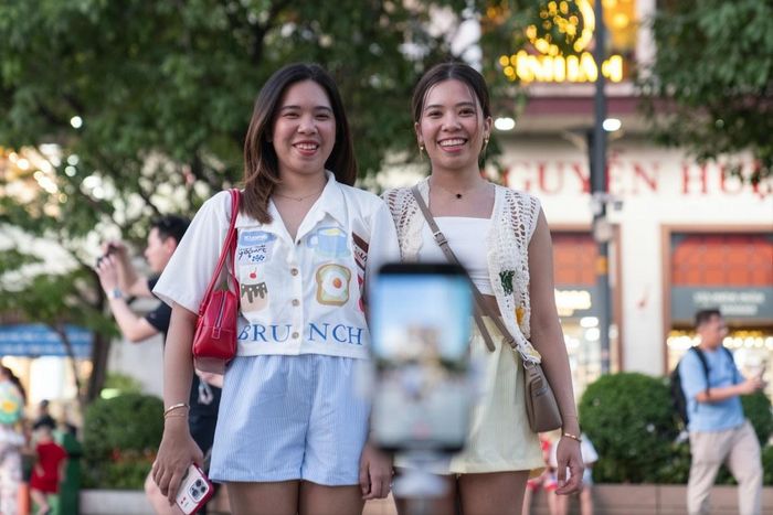  Hai nữ du khách quốc tế đang quay video timelapse tại phố đi bộ Nguyễn Huệ tháng 4/2025. Ảnh: Linh Huỳnh. 