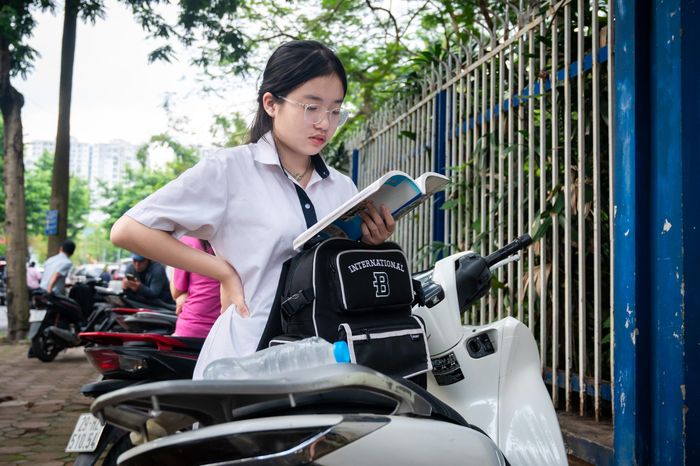  Nhiều em tranh thủ mở tập ghi đề cương để xem lại lần cuối. Có em đứng nép dưới bóng cây, lẩm nhẩm kiến thức, có em ngồi trên xe máy của bố mẹ, mắt không rời cuốn vở chi chít chữ. 