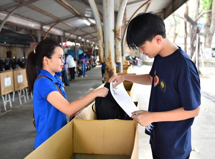 Tình nguyện viên hướng dẫn thí sinh gửi đồ trước khi vào phòng thi