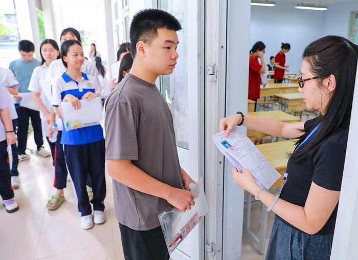 Giám thị kiểm tra thông tin thí sinh trước khi vào phòng thi tại Điểm thi trường THPT Đoàn Kết - Hai Bà Trưng (phường Bạch Mai). Ảnh: Khánh Hòa - TTXVN