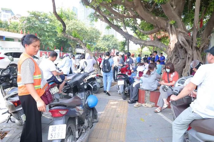 Nhiều phụ huynh ngồi chờ dưới bóng cây để tránh cái nắng mùa hè.