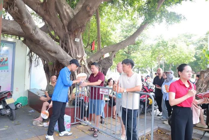Các sinh viên tình nguyên trao quạt và nước cho các phụ huynh học sinh trong chiều hè nóng bức.