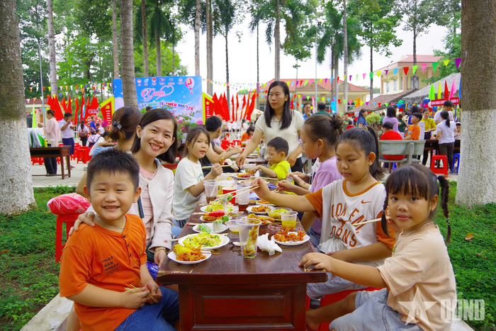 Các cháu thiếu nhi cùng cha mẹ dùng bữa tiệc tự chọn trong khuôn viên đơn vị.
