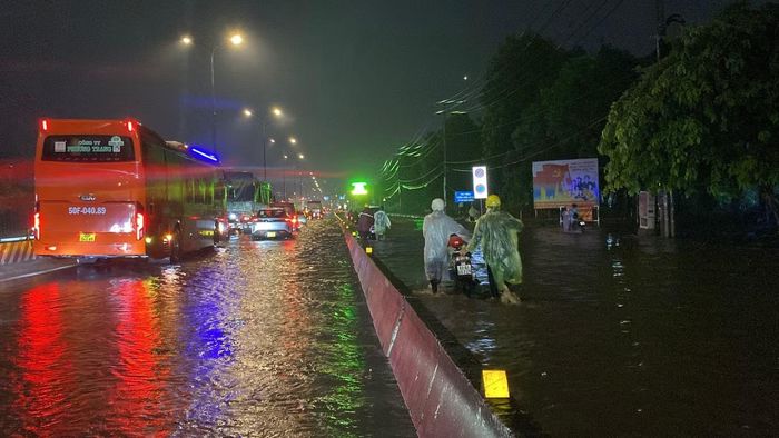 Trên quốc lộ 1, đoạn qua phường An Lạc, nước dâng cao khiến các phương tiện phải di chuyển chậm, nhiều xe máy chọn quay đầu tìm hướng đi khác để tránh ngập. Ảnh: Hữu Huy