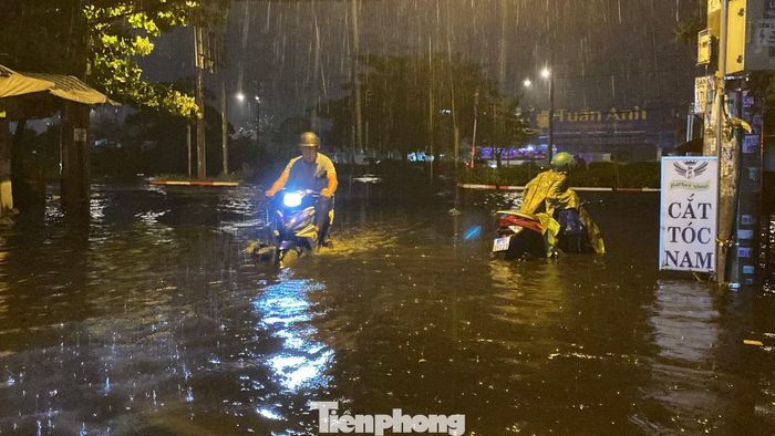 Nước ngập sâu, người và phương tiện di chuyển khó khăn qua điểm ngập. Ảnh: Hữu Huy