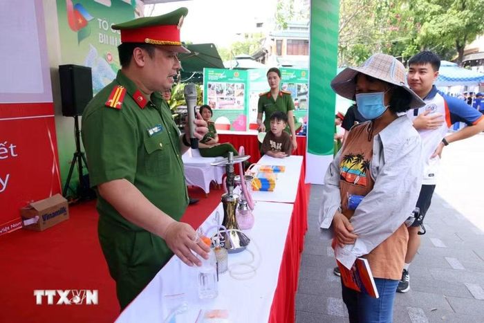 Người dân được các chiến sỹ Công an Thủ đô tuyên truyền về tác hại và cách phòng, chống ma túy tại buổi lễ. (Ảnh: Phạm Kiên/TTXVN)
