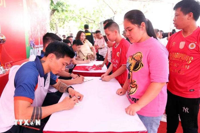 Người dân và các em nhỏ hào hứng giao lưu, xin chữ ký các cầu thủ CLB bóng đá Công an Hà Nội tại buổi lễ. (Ảnh: Phạm Kiên/TTXVN)