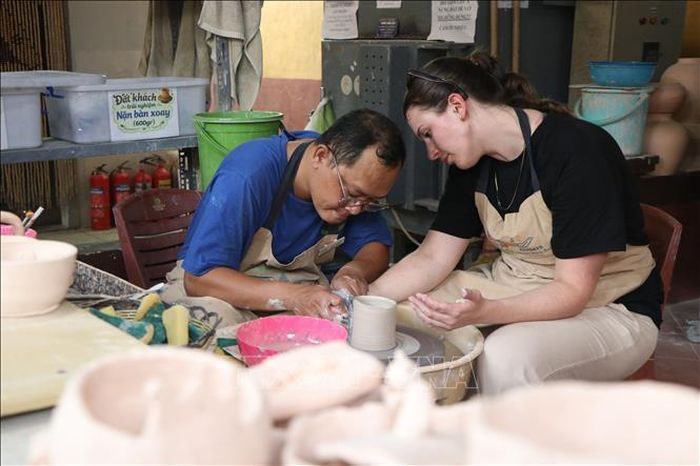 Học viên Trung tâm Hy vọng Huế hướng dẫn du khách làm gốm.