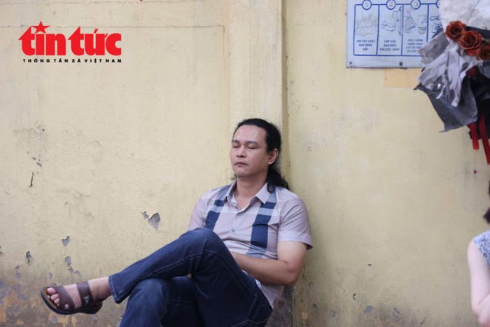 Một phụ huynh tranh thủ chợp mắt bên tường trong lúc chờ thí sinh làm bài tại điểm thi Trường THPT Phan Đình Phùng, Hà Nội.
