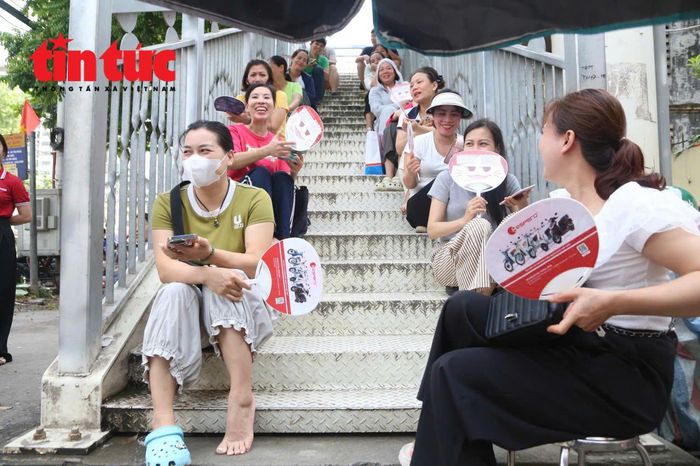 Phụ huynh đợi con tại điểm thi Trường trung học phổ thông Trần Hưng Đạo. Dù phải chờ đợi nhiều giờ, các phụ huynh vẫn kiên nhẫn đồng hành cùng con trong kỳ thi quan trọng.