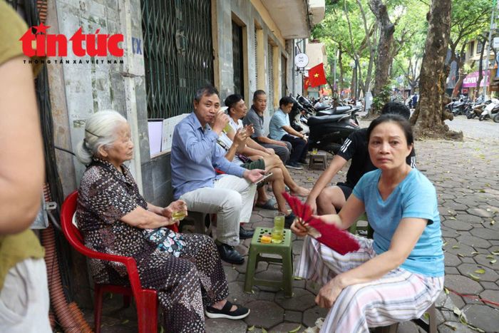 Nhiều phụ huynh ngồi chờ trên vỉa hè, khu vực các cửa hàng gần điểm thi.