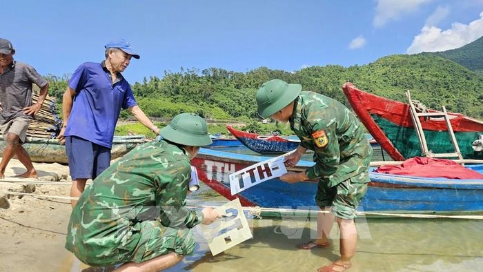Lực lượng bộ đội biên phòng thành phòng Huế cùng ngư dân sơn biển số lên thân tàu theo đúng quy định. Ảnh: Mai Trang - TTXVN