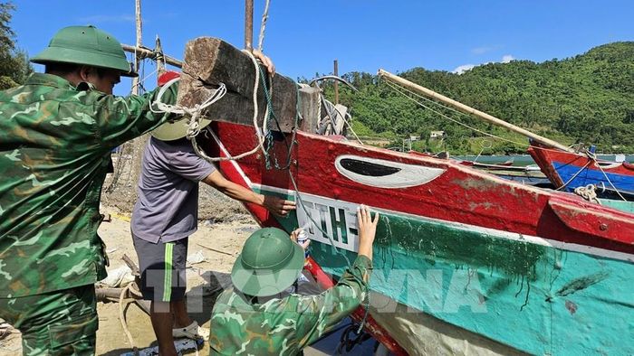 Lực lượng bộ đội biên phòng thành phố Huế giúp ngư dân địa phương sơn biển số lên thân tàu theo đúng quy định. Ảnh: Mai Trang - TTXVN