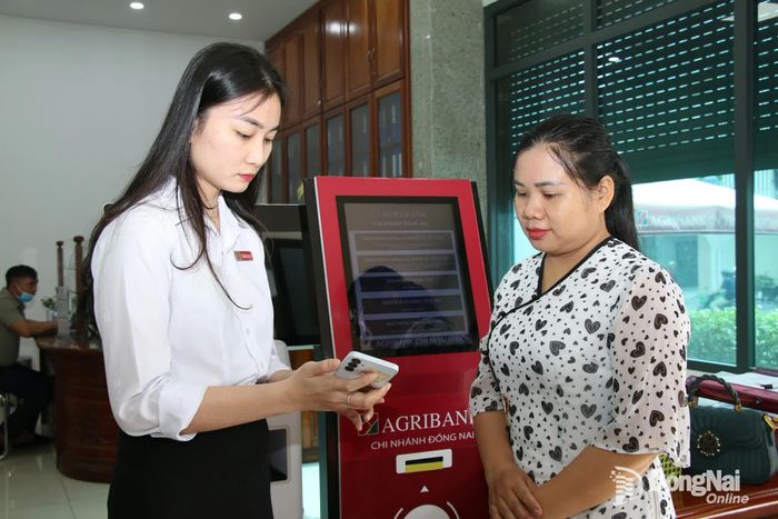 Nhân viên Agribank chi nhánh Đồng Nai (phường Trấn Biên) hướng dẫn khách hàng sử dụng tiện ích trên ứng dụng ngân hàng số. Ảnh: Hải Quân