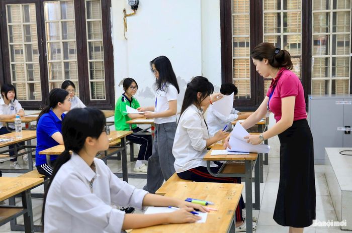 Cán bộ coi thi phát giấy thi cho thí sinh dự thi môn ngữ văn.
