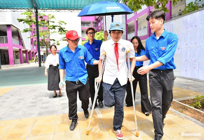 Thanh niên tình nguyện giúp đỡ một thí sinh tại điểm thi Trường THCS Nguyễn Trãi (phường Ba Đình).